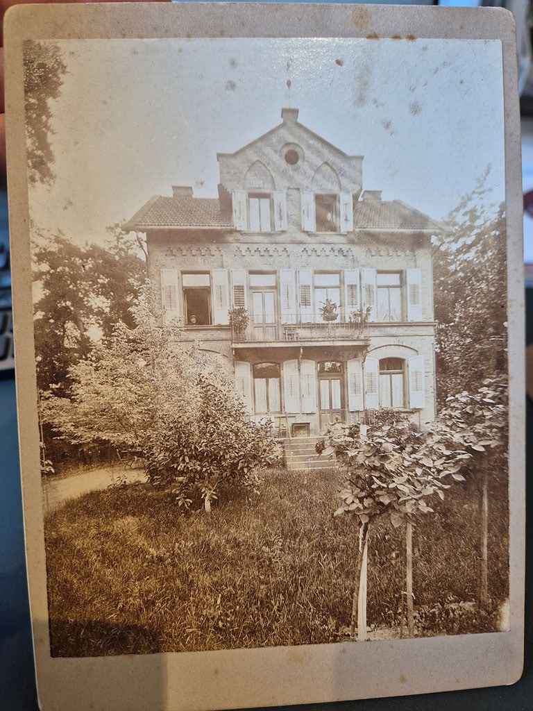 Erste Vorlage für die Fotorestaurierung Vergilbtes altes Foto eines historischen Gebäudes mit sichtbaren Alterungsspuren und Randbereichen der ursprünglichen Vorlage.