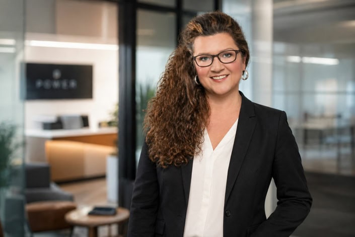 Businessporträt einer Frau mit lockigem Haar im dunklen Blazer
