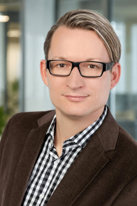 Klassisches Businessportrait vor modernem Bürohintergrund Businessporträt eines Mannes mit Brille vor hellem Bürohintergrund