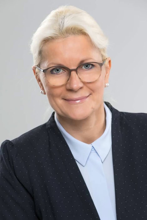 Elegantes Businessporträt einer Frau mit Brille vor neutralem Hintergrund