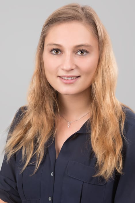 Junge Frau auf elegantem Bewerbungsfoto vor hellem Hintergrund