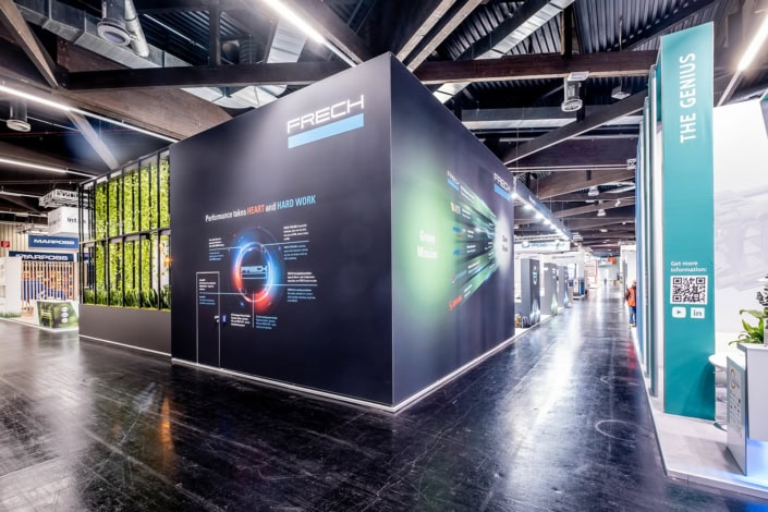 Moderner Messestand mit dunklem Design und beleuchteter Präsentationsfläche