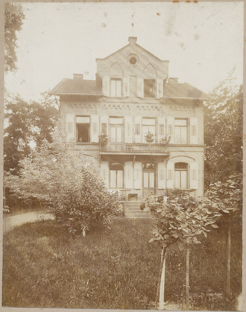 Originalscan als Grundlage der Restaurierung Hochauflösender Scan eines vergilbten historischen Fotos mit altem Gebäude und Gartenstruktur.