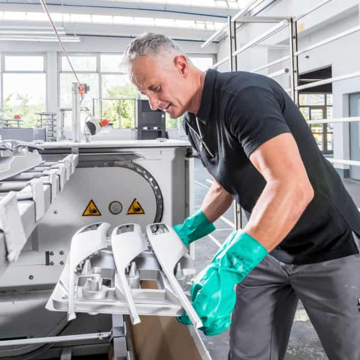 Mitarbeiter reinigt eine Maschine in einer industriellen Arbeitsumgebung