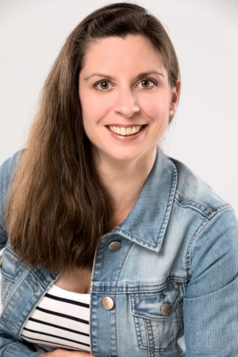 Frau auf legerem Bewerbungsfoto mit Jeansjacke vor hellem Hintergrund