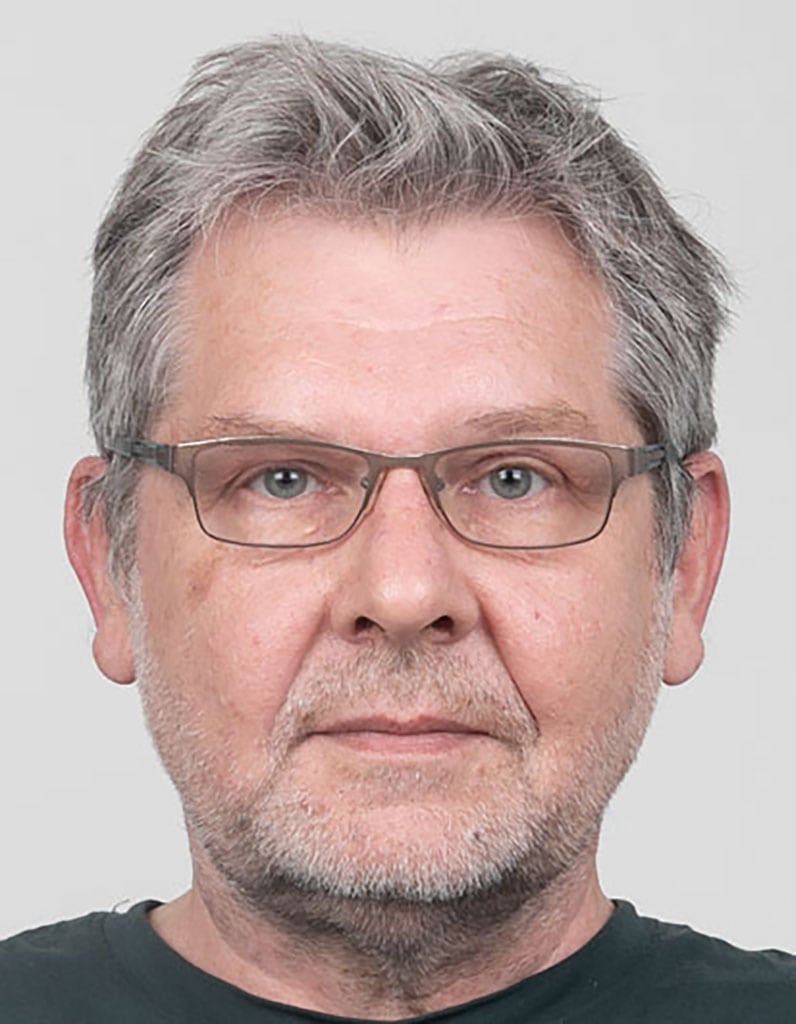 Martin Kaczmarski, ARTARCO Fotostudio Fürth Porträt von Martin Kaczmarski vor hellem Hintergrund, frontal fotografiert mit Brille und grauem Haar.