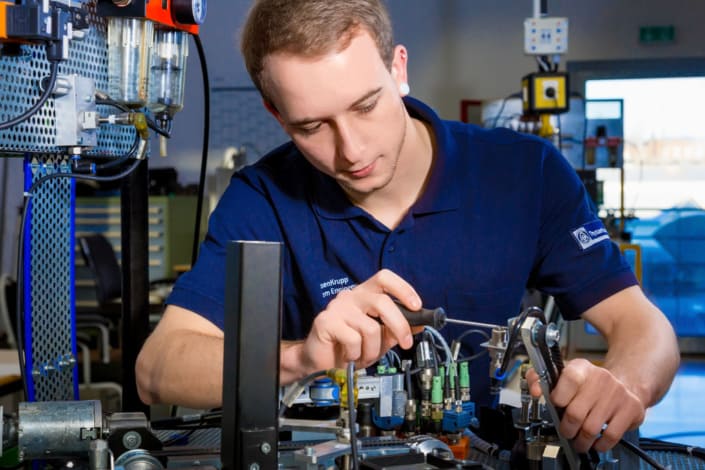 Mitarbeiter montiert ein Bauteil in einer technischen Produktionsumgebung