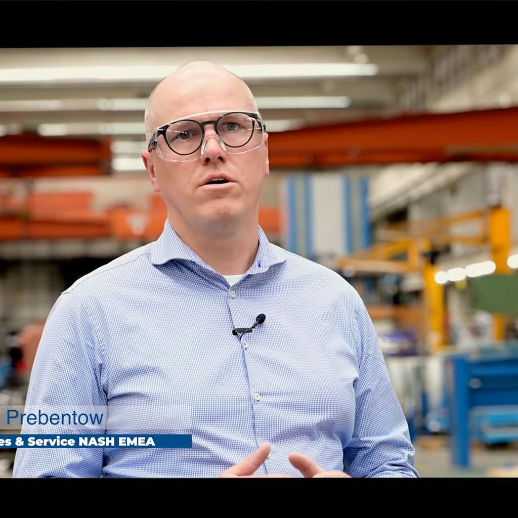 Mann mit Ansteckmikrofon spricht während einer Videoproduktion in einer Industriehalle.